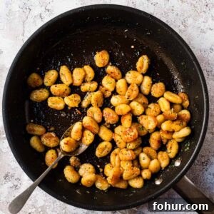 Pan fried gnocchi in a skillet with herbs and parmesan.