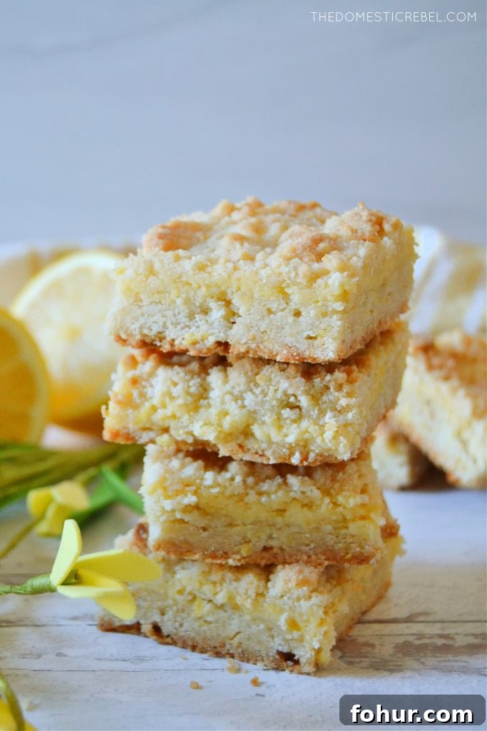 a quadruple stack of lemon crumble bars on white wood