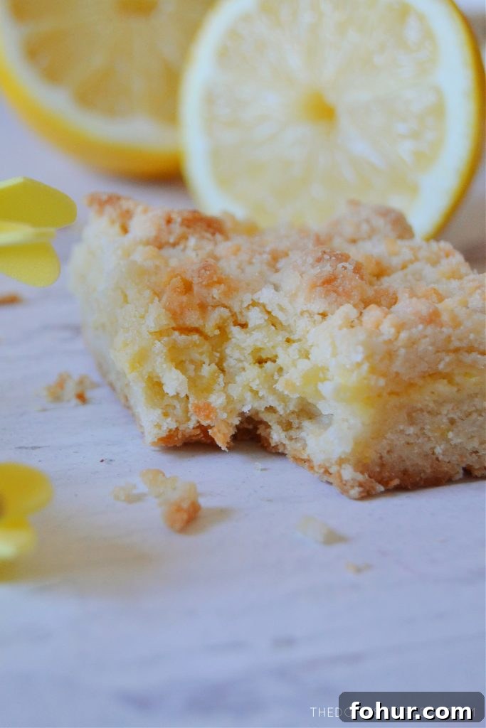 lemon crumble bar with bite missing on white wood