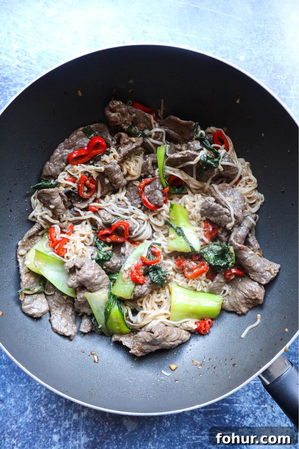 Pho Xao: Vietnamese Stir-Fried Beef and Rice Noodles 6 wok with stir fry beef, noodles, and vegetables cooked in a wok together.