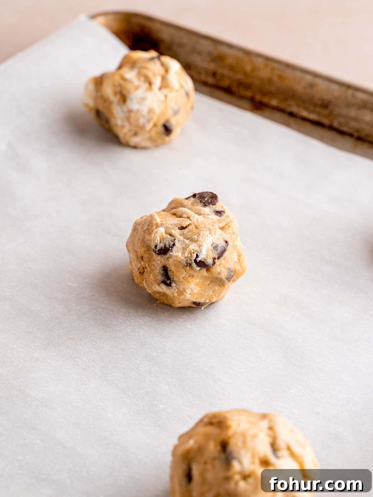 S'mores Cookies: Gooey Marshmallow and Chocolate Recipe 8 Cookie dough balls on a parchment paper lined baking sheet.
