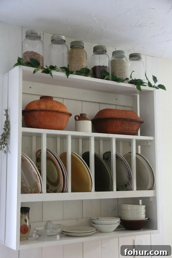 A white, open kitchen shelve with a plate rack in the centers and shelves above and below