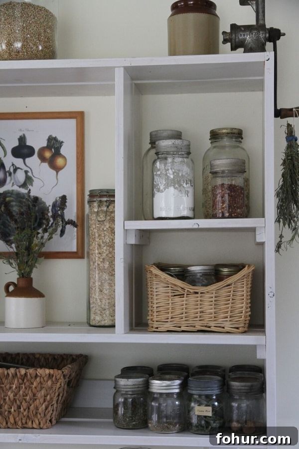 An open kitchen shelf displaying jars of dry goods, baskets and a bouquet of lavender