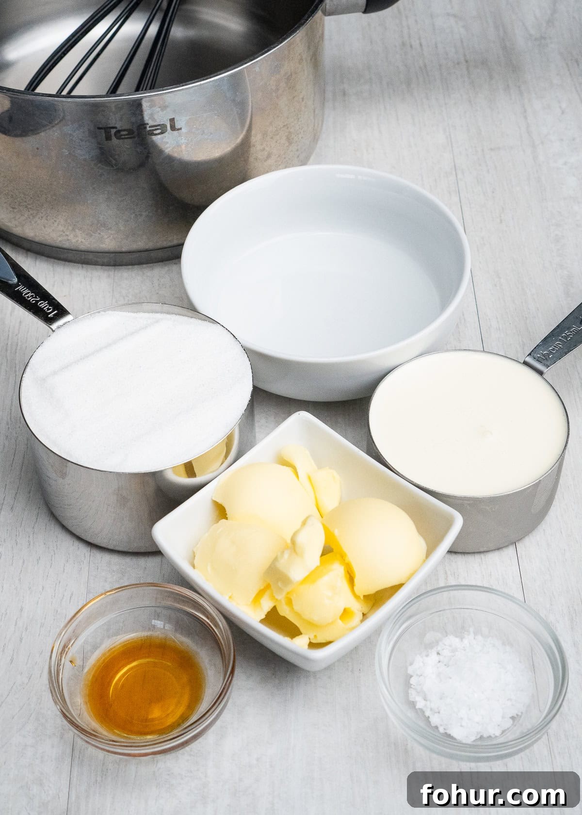 How to Make Salted Caramel Sauce 4 A cooking pot with whisk, bowl of water, butter, caster sugar, cream, salt and vanilla