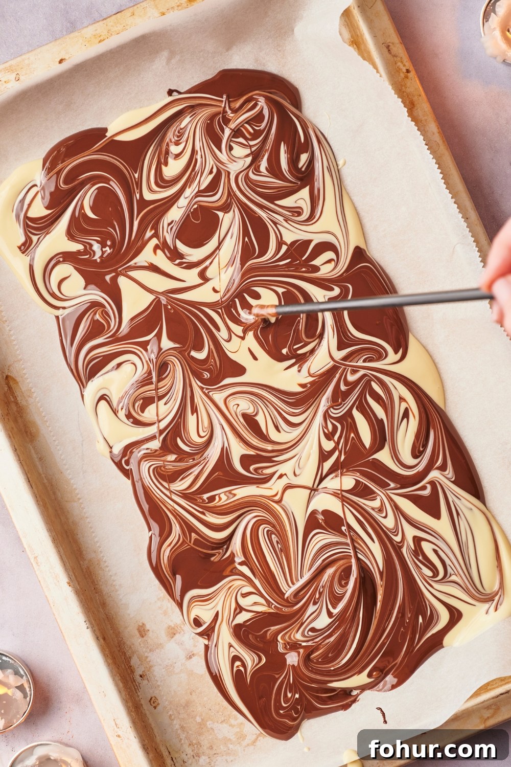 No-Bake Peppermint Bark Ready in 5 Minutes 8 Melted chocolate in a checkered pattern on parchment paper. A straw is creating a marbled pattern.