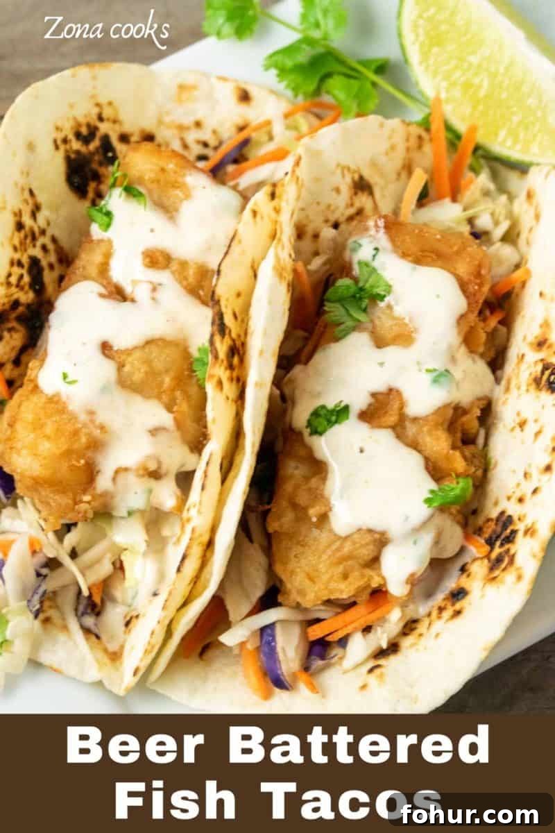 Crispy Beer-Battered Fish Tacos with Lime Slaw 2 two Beer Battered Fish Tacos with coleslaw on a plate.