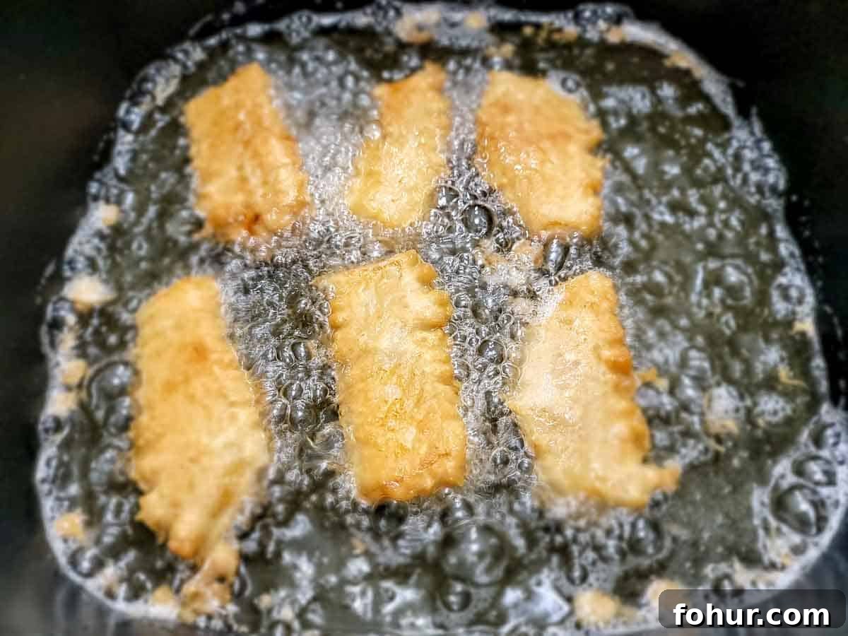 Crispy Beer-Battered Fish Tacos with Lime Slaw 7 6 beer battered cod filets frying in an electric skillet.
