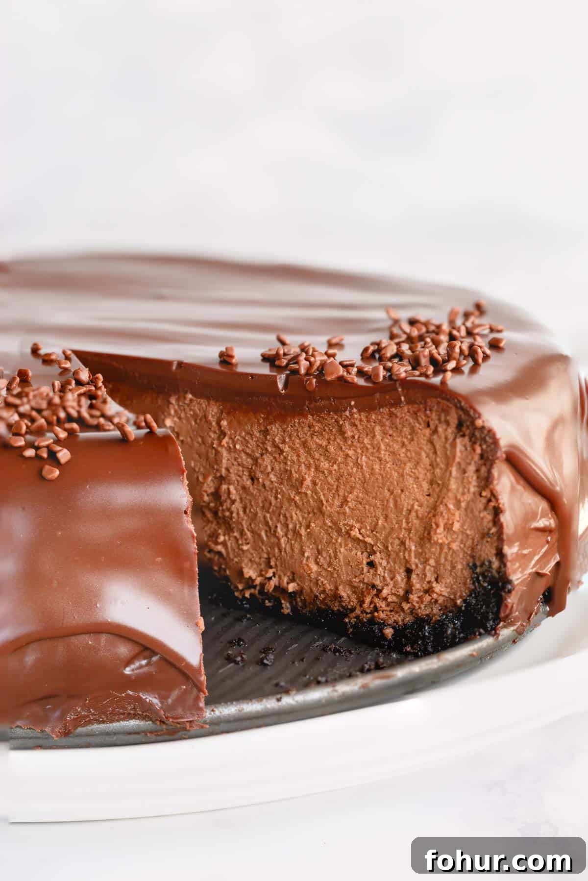 Decadent Chocolate Cheesecake Recipe with Ganache 2 Supreme chocolate cheesecake with a slice missing.