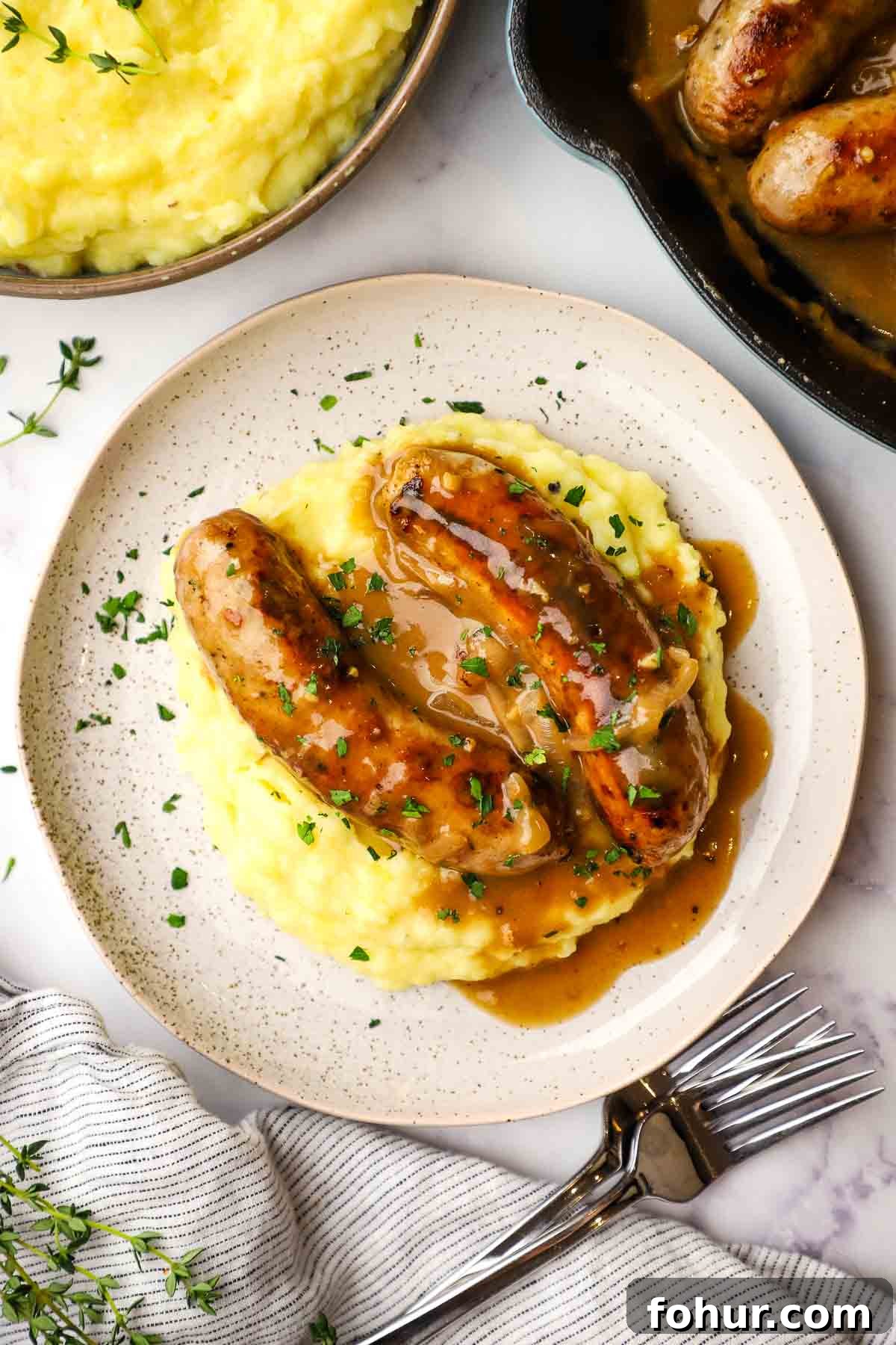 Classic British Bangers and Mash with Rich Onion Gravy 11 a plate of bangers and mash with gravy on top