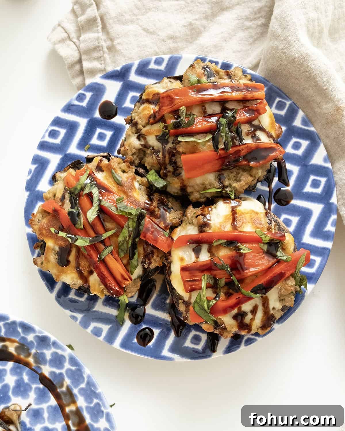 Italian-Style Baked Stuffed Portobello Mushrooms 11 Baked Italian stuffed portobello mushrooms topped with roasted red peppers, basil and balsamic glaze on a plate.