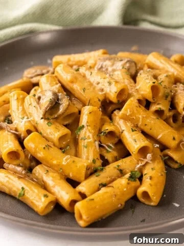 Creamy mushroom pasta on a plate garnished with parmesan.