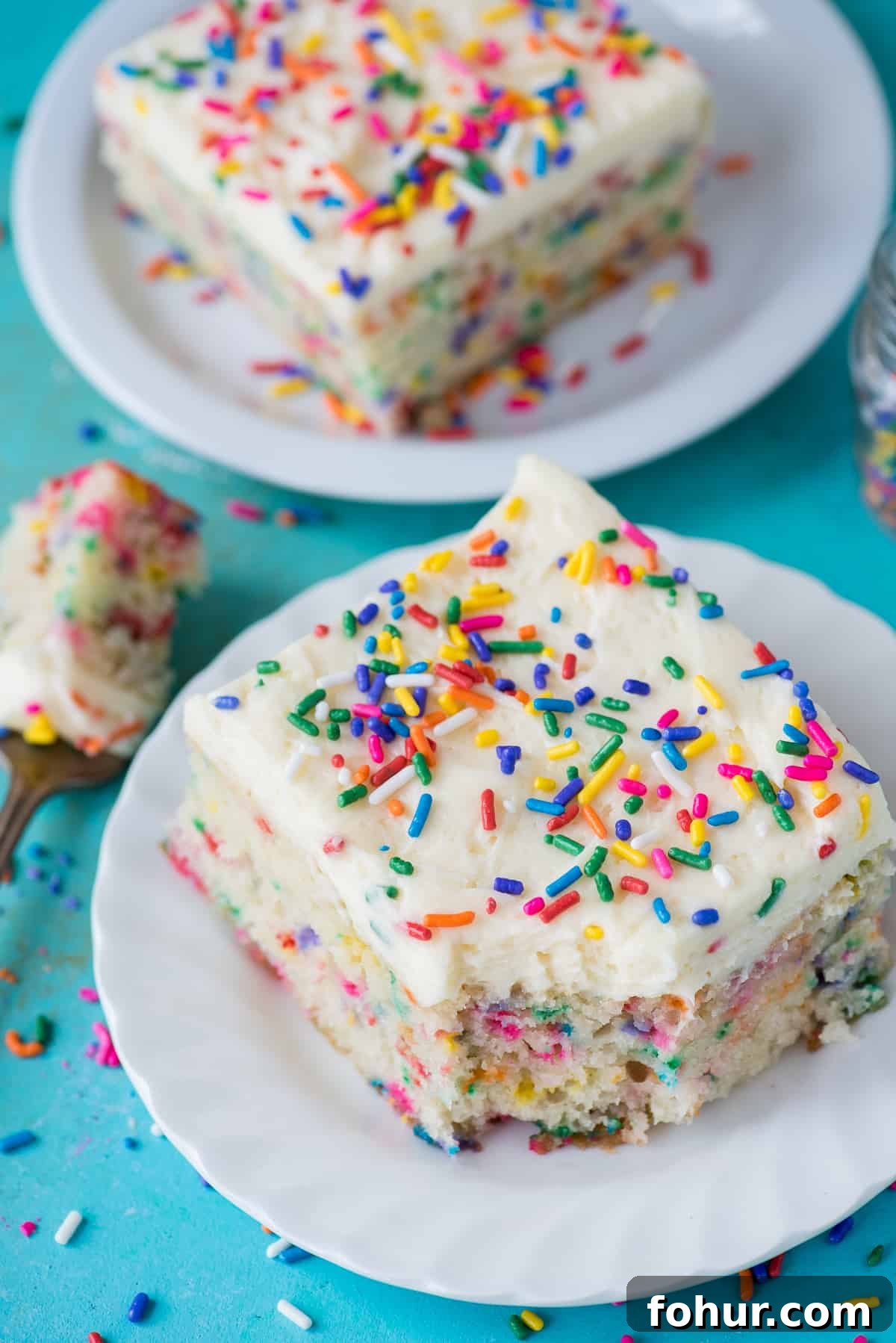 How to Make a Classic Funfetti Cake 2 two pieces of funfetti cake on white plates on teal background