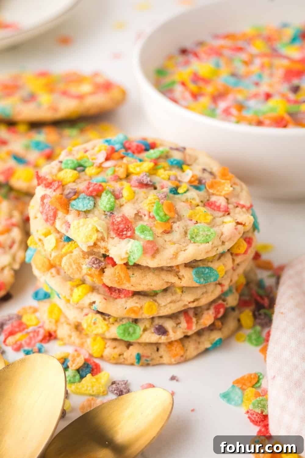 Fruity Pebbles Cookies Recipe for Crispy Colorful Treats 3 a stack of colorful Fruity Pebbles cookies in front of a white bowl of cereal.