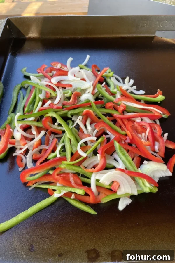 Philly Cheesesteak Recipe: Classic Homemade Sandwich 3 pile of red pepper, green pepper and onions on a griddle