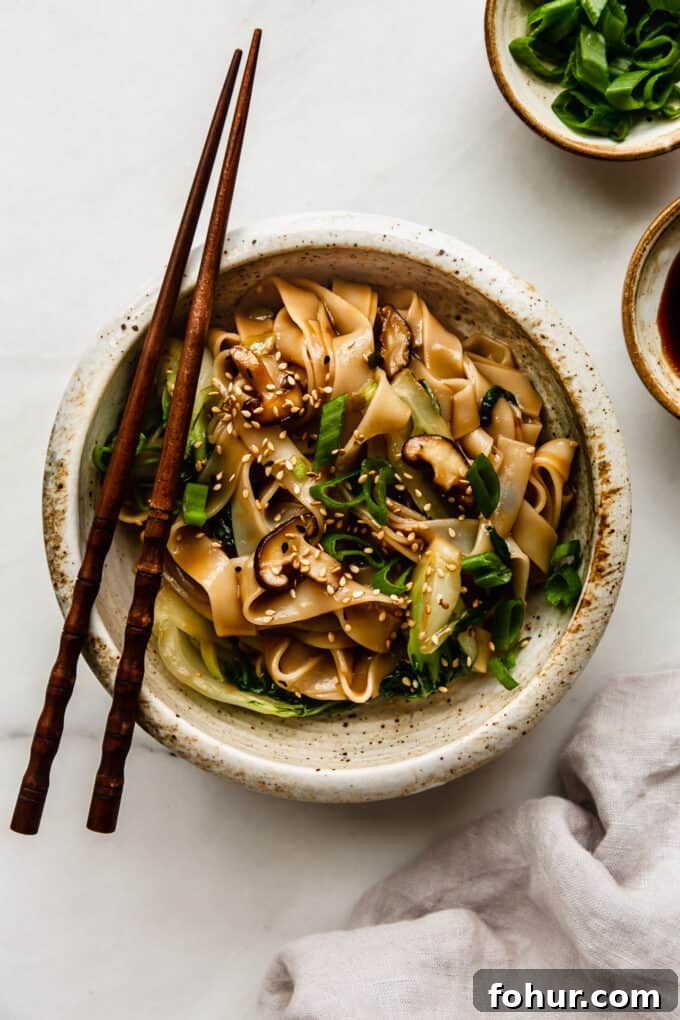 a bowl of ho fun noodles on a marble board with a napkin on the side