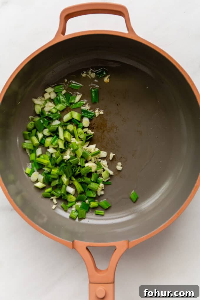 green onions and garlic in a pink pan