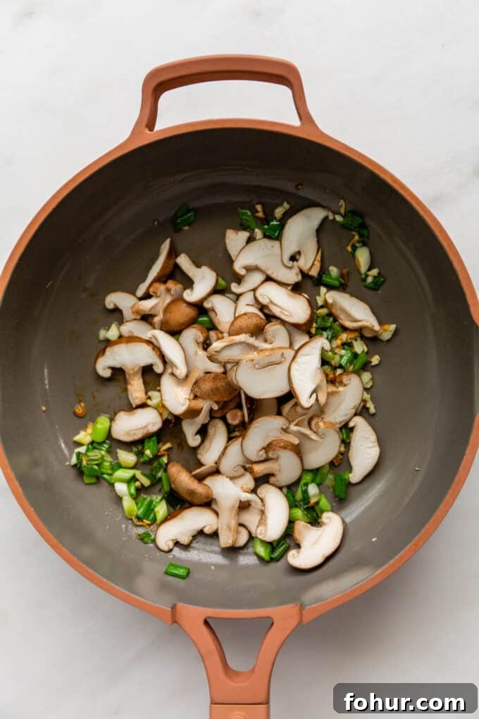 green onions, garlic and shiitake mushrooms in a pink pan