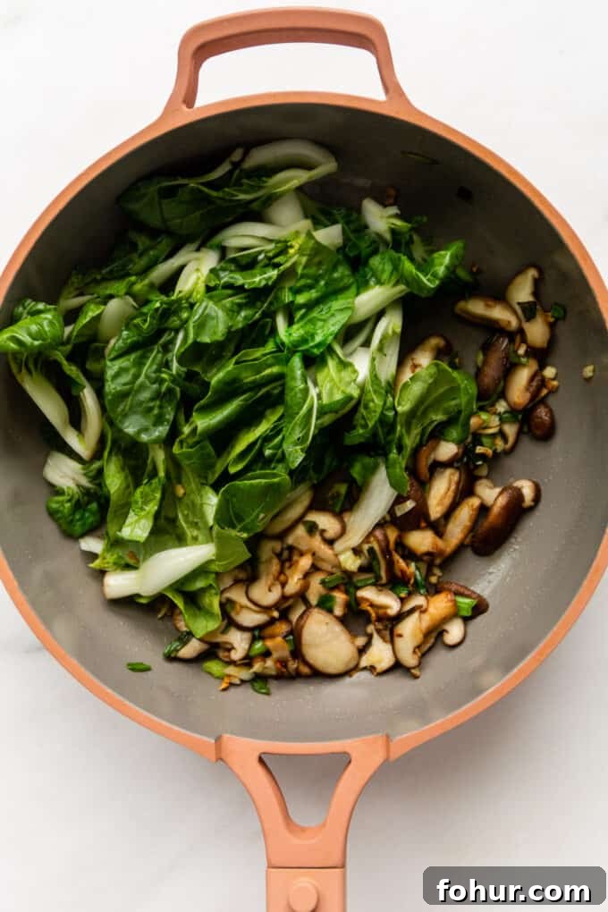 mushrooms and bok choy in a pink pan