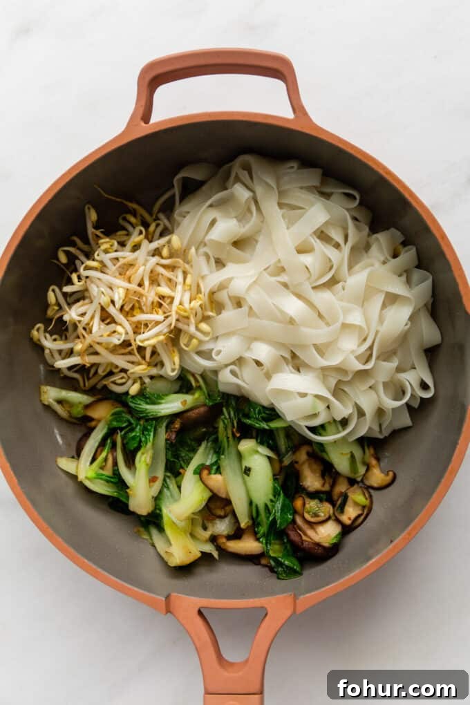 vegetables and rice noodles in a pink pan