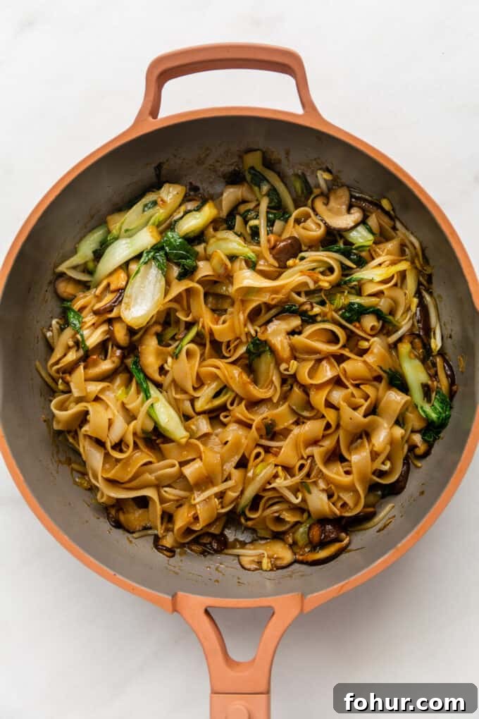 ho fun noodles stir fried in a pink pan
