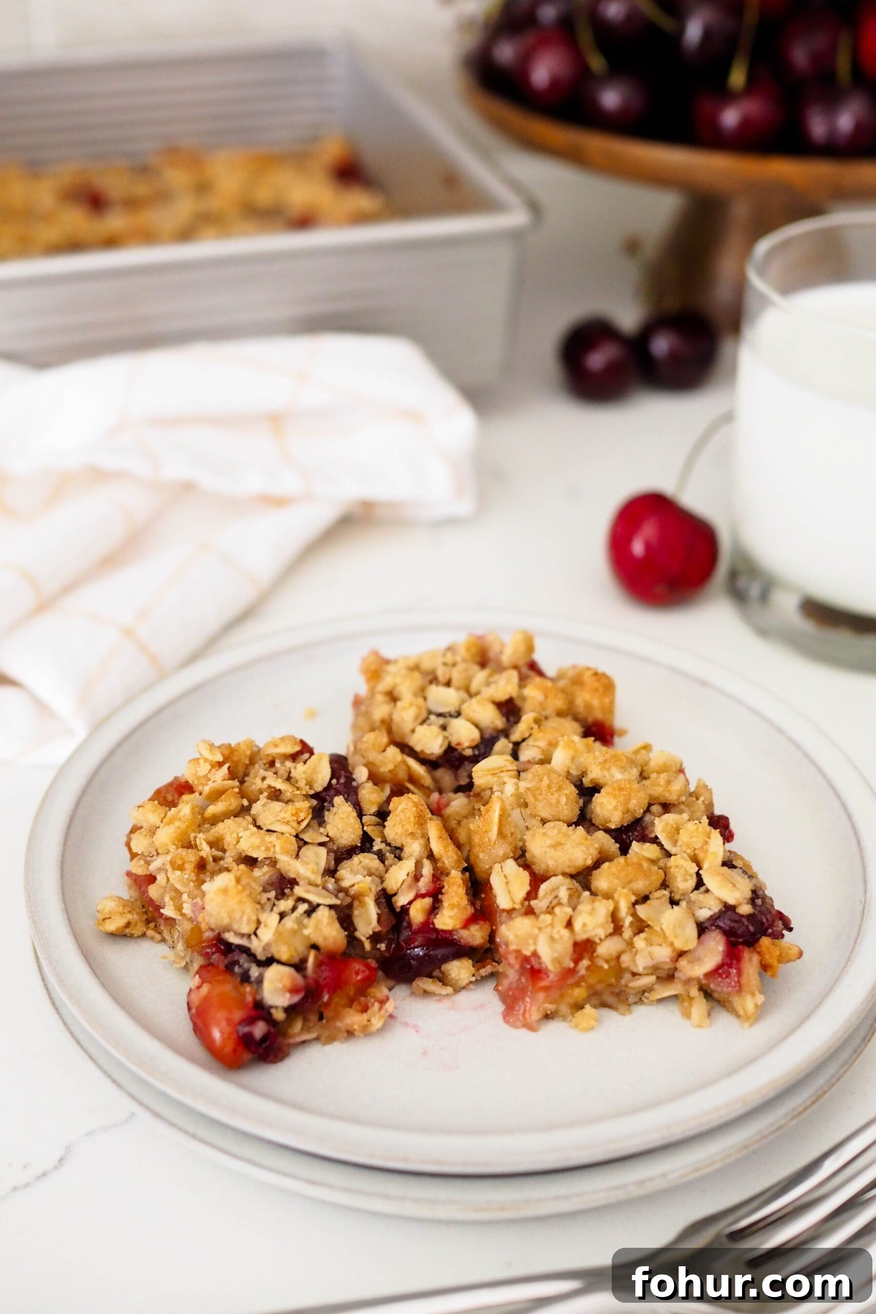 Cherry Crumble Bars with Buttery Oat Crust 2 Three pieces of cherry crumble rest on a plate.