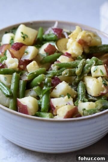 A large bowl of green beans and potato salad, perfect for feeding a crowd.