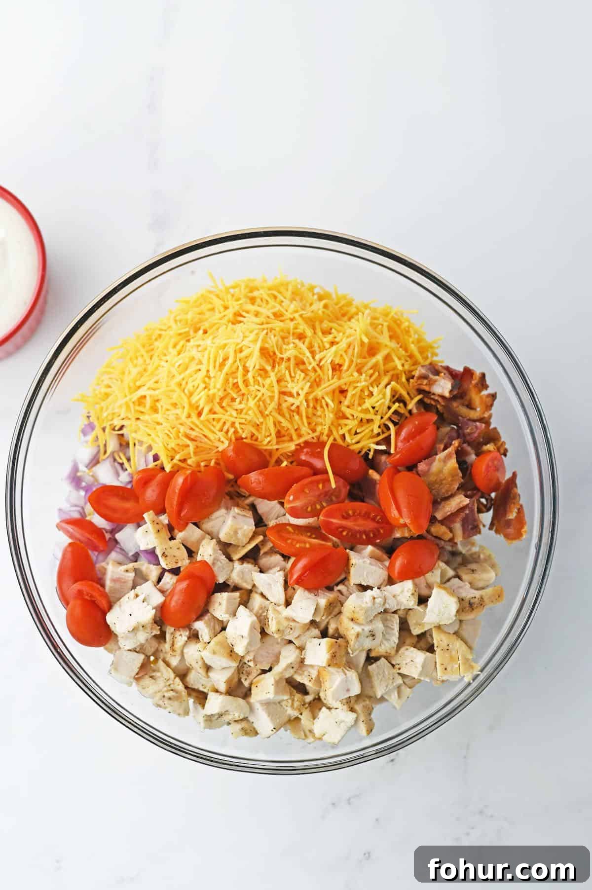 How to make chicken bacon ranch pasta salad, with all the toppings in a large bowl.
