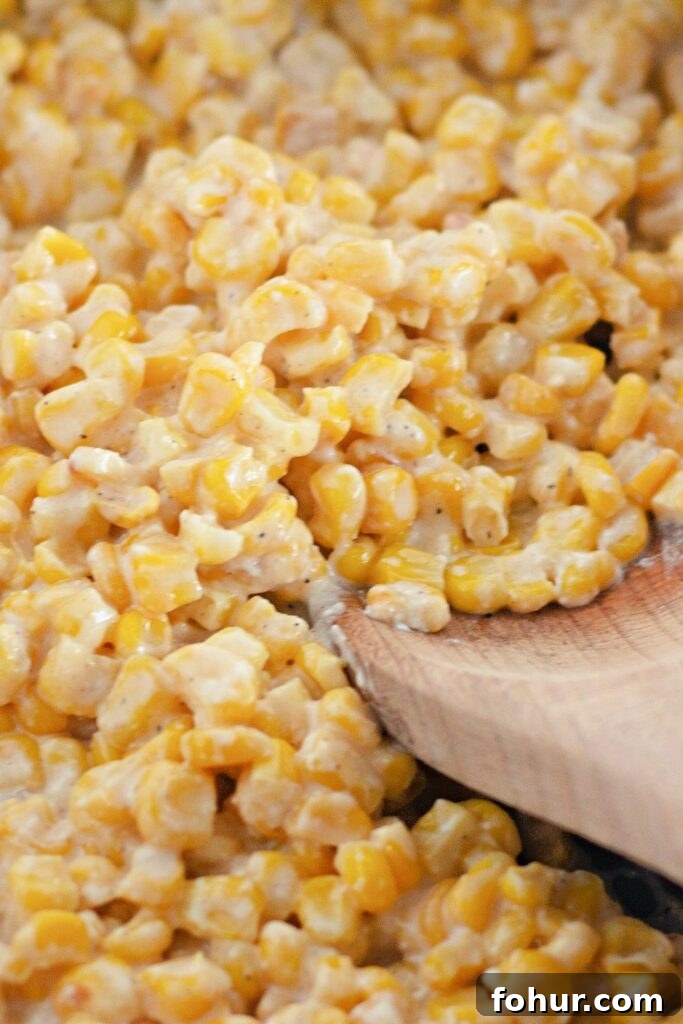 corn in a pan with a wooden spoon on the side of bowl