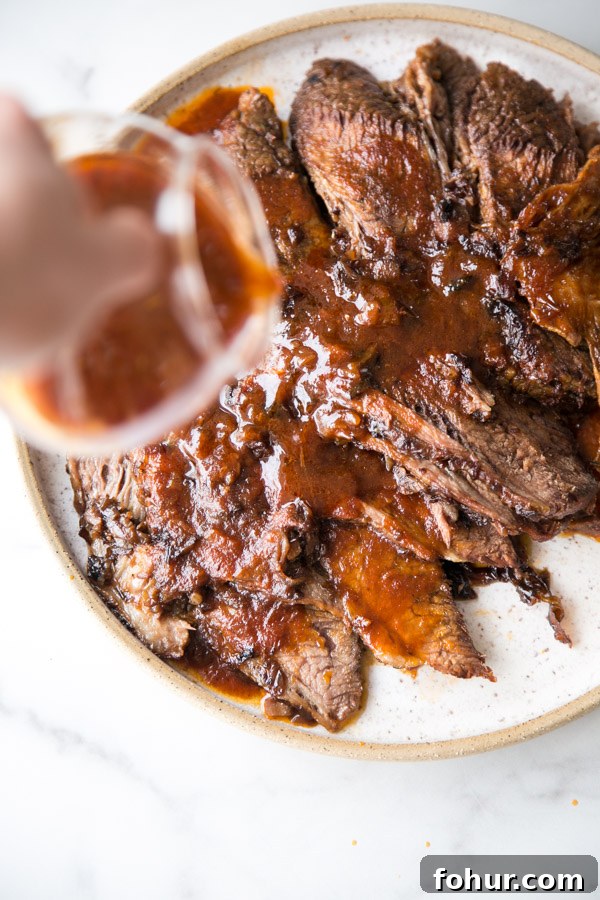Passover Brisket Recipe for Any Jewish Holiday Dinner 7 hand pouring sauce over sliced jewish brisket on a platter