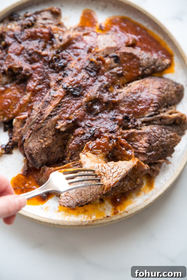 Passover Brisket Recipe for Any Jewish Holiday Dinner 8 hand holding forkful of sliced jewish brisket on a platter