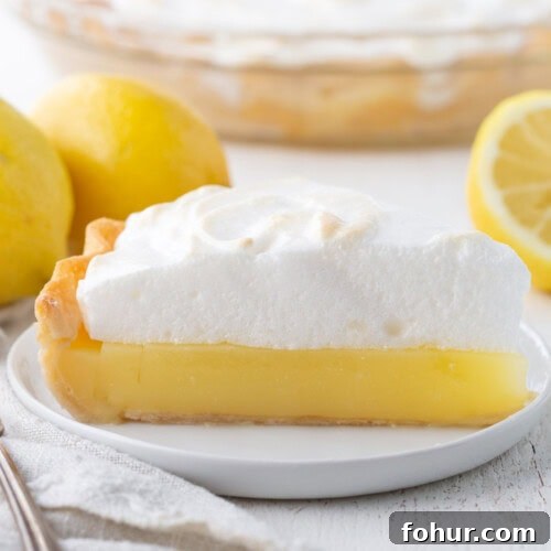 slice of lemon pie with a yellow lemon layer topped with fluffy meringue.