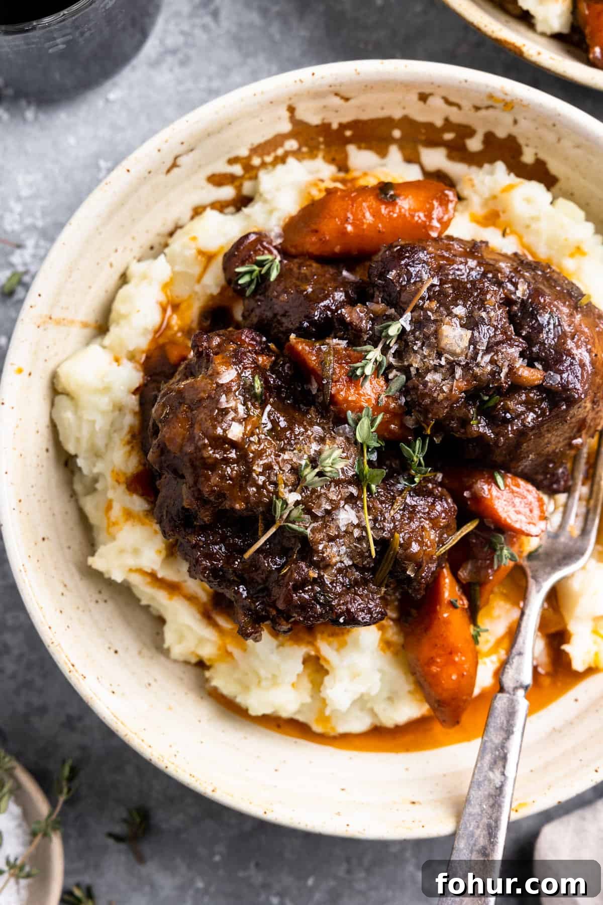 Slow-Braised Oxtail Recipe with Red Wine and Herbs 2 Plate with mashed potatoes, oxtails, and cooked carrots.