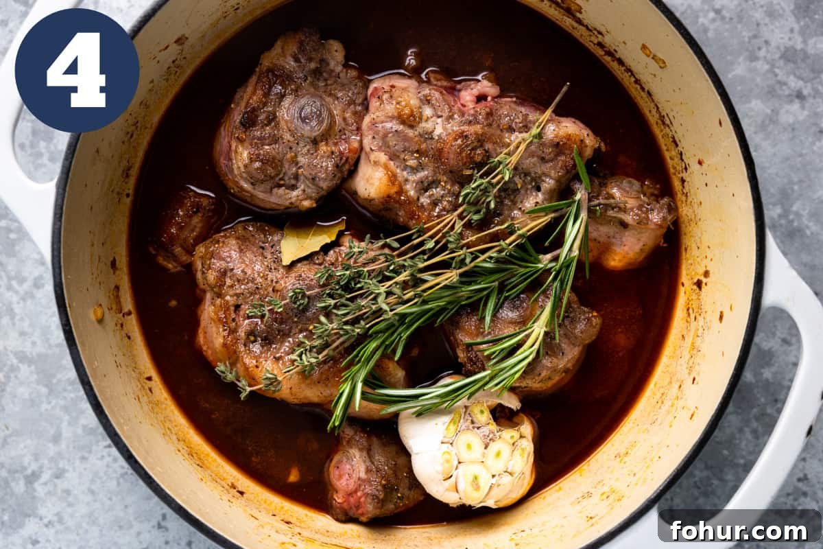 Slow-Braised Oxtail Recipe with Red Wine and Herbs 7 Oxtails in a dutch oven with broth, garlic, and herbs.