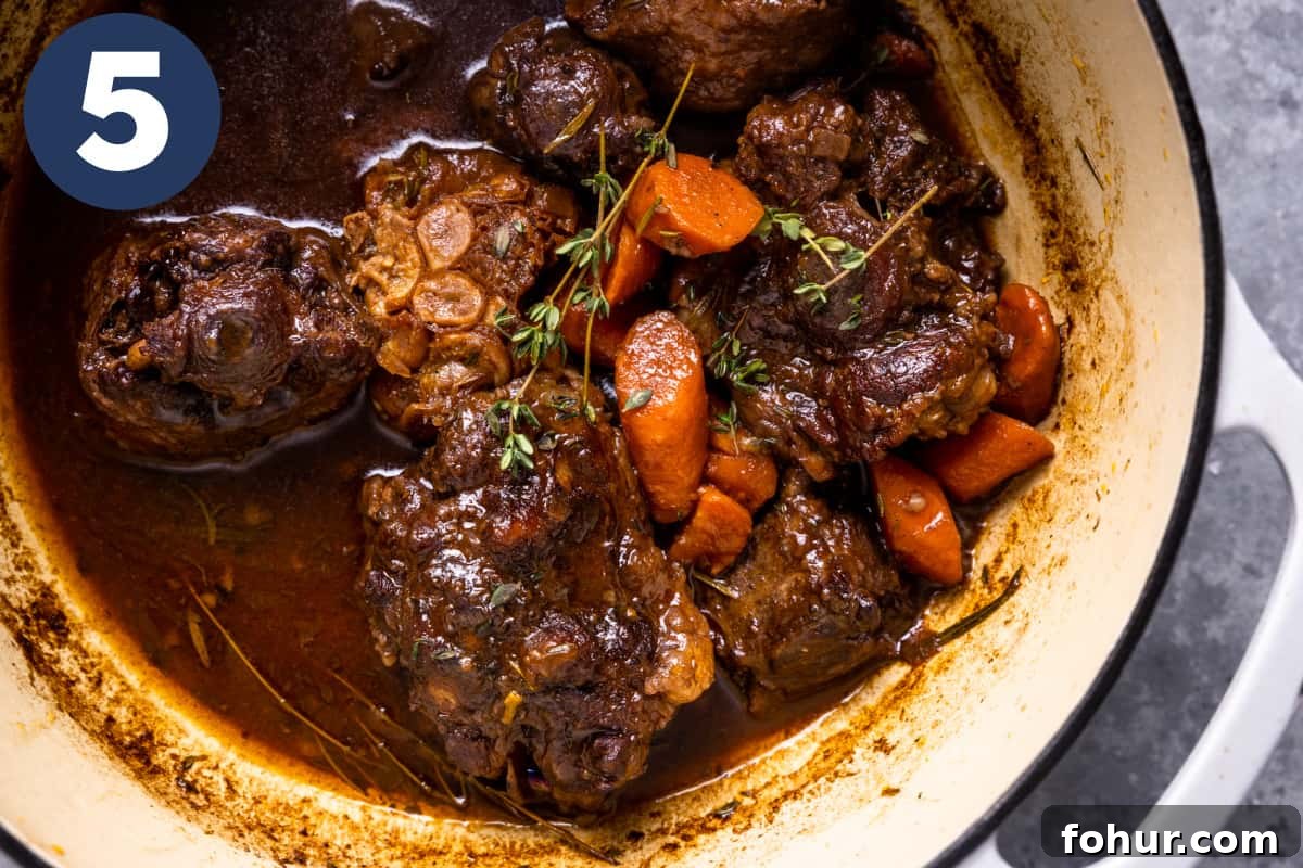 Slow-Braised Oxtail Recipe with Red Wine and Herbs 8 Braised oxtails in a dutch oven with carrots, garlic, and fresh herbs.