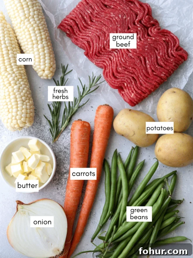 Foil dinner ingredients including corn, ground beef, fresh herbs, butter, carrots, potatoes, onion, and green beans