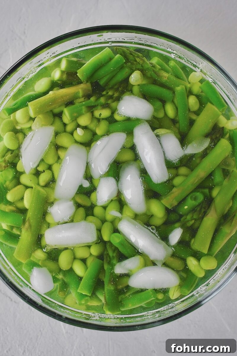 Creamy Green Goddess Potato Salad Recipe 6 Cooked green beans, asparagus, and edamame, placed in a bowl of ice water to shock them and stop the cooking after blanching in the boiling water.