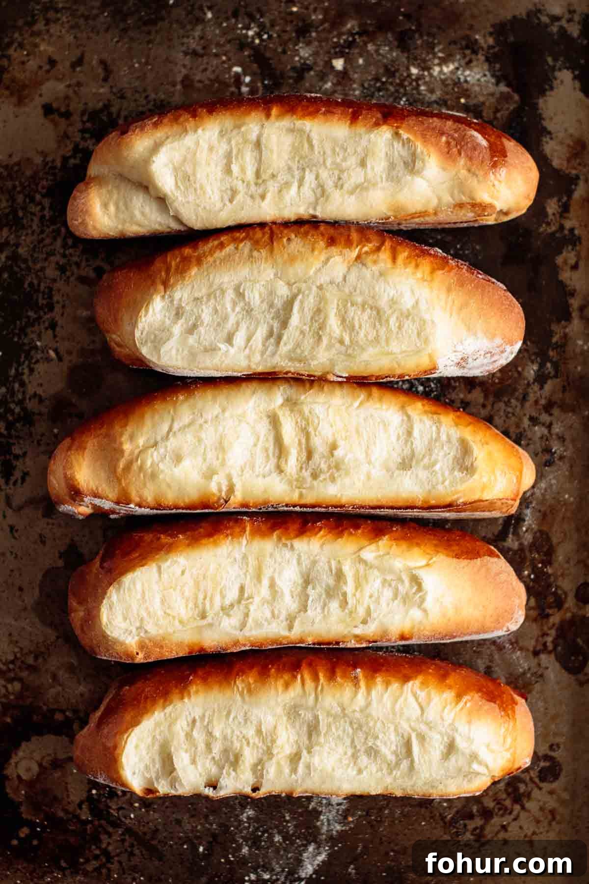 How to Make Brioche Hot Dog Buns from Scratch 2 Baked brioche hot dog buns on a baking sheet.