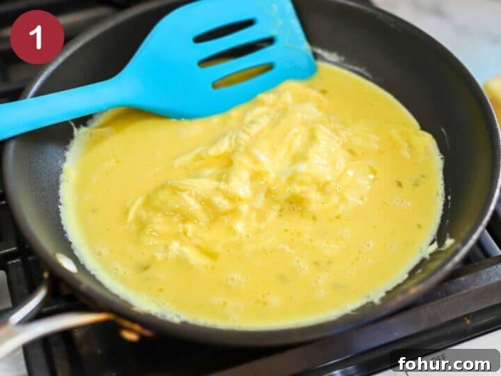 Breakfast Bagel Recipe with Egg, Bacon & Melted Cheese 3 Frying pan with scrambled eggs cooking.