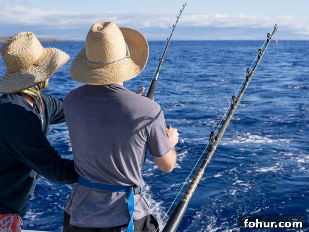 Two men with wide brimmed sun hats on, fishing off a boat out to sea.