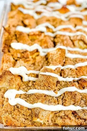 Baked overnight french toast casserole in a glass baking dish, topped with cream cheese glaze.