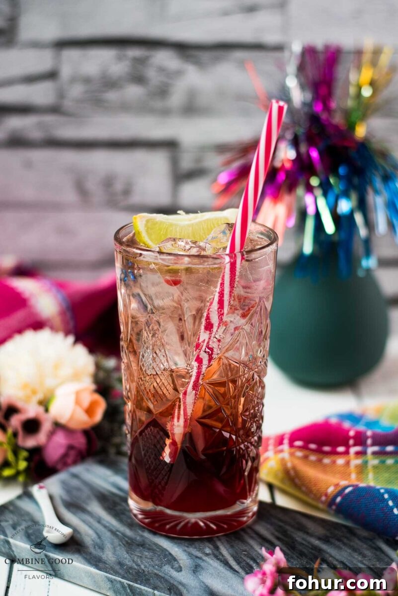 Raspberry Gin and Tonic Cocktail Recipe 2 Highball glass filled with raspberry gin and tonic, garnished with a lime wedge and a straw.