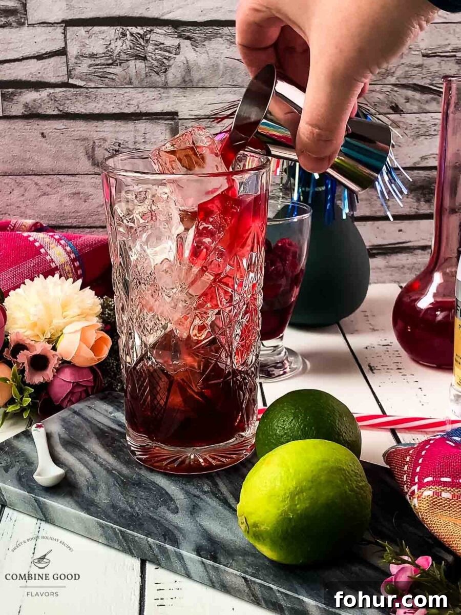 Raspberry Gin and Tonic Cocktail Recipe 6 Pouring raspberry syrup into the glass.
