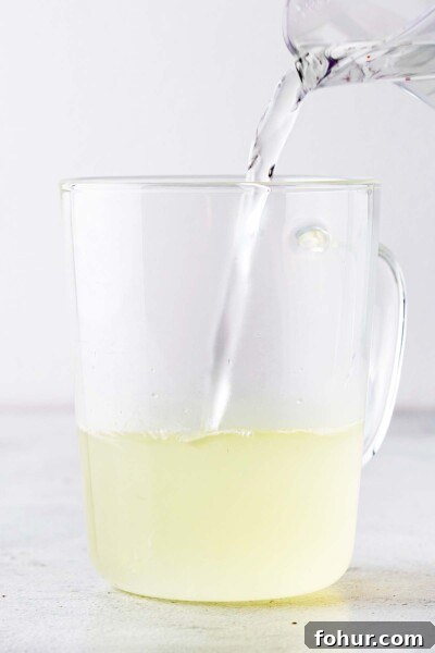 How to Make Homemade Lemon Tea: Fresh Citrus Recipe 4 Pouring hot water into a cup with lemon juice.