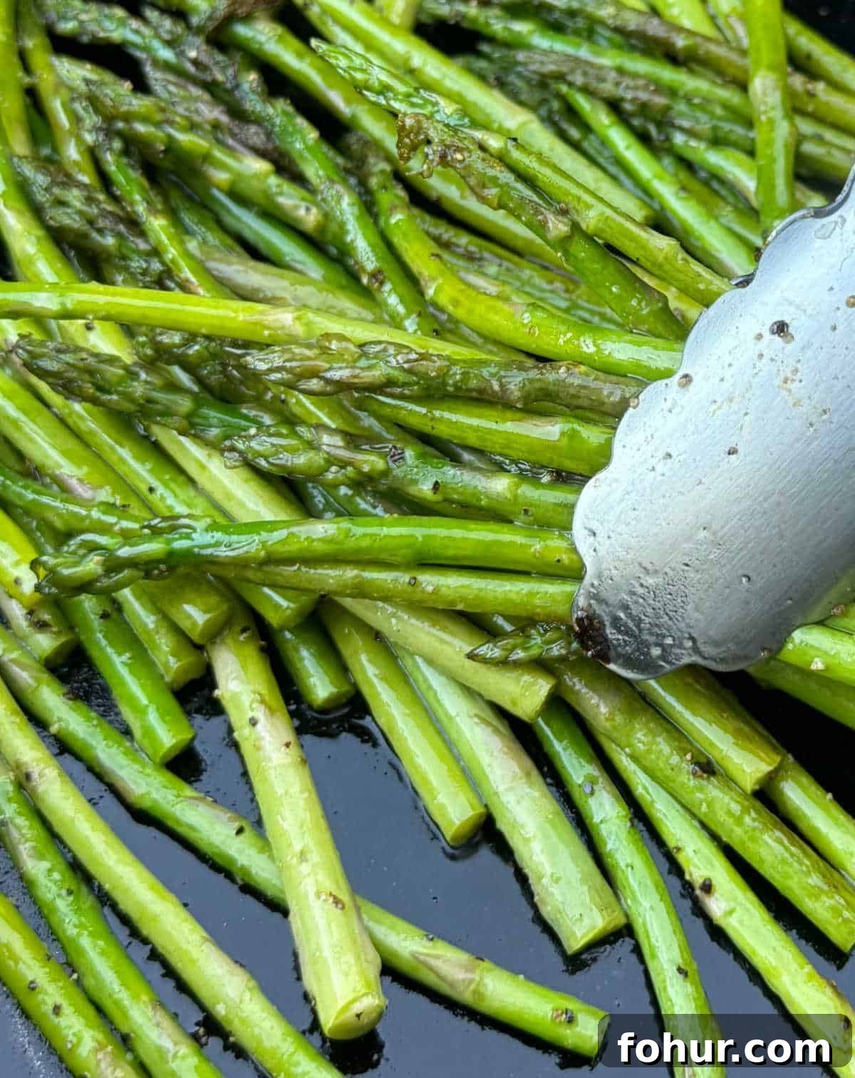 Blackstone Griddle Asparagus Recipe: Quick Grilled Asparagus 8 grilled asparagus in tongs.