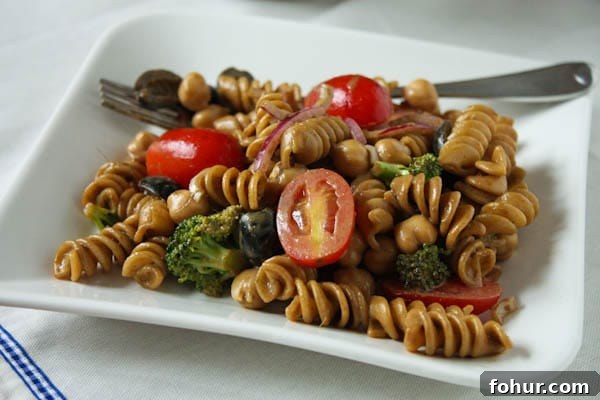 Pasta Salad with Balsamic Basil Vinaigrette pasta salad with cherry tomatoes, olives, red onions, and broccoli on a plate with a fork