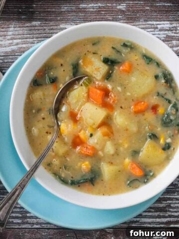 Metal spoon in a bowl of vegan potato soup.