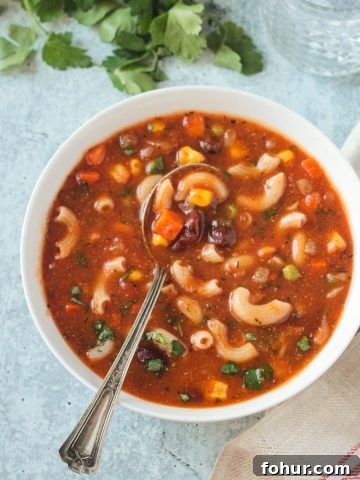 Metal spoon in a bowl of vegan minestrone soup.