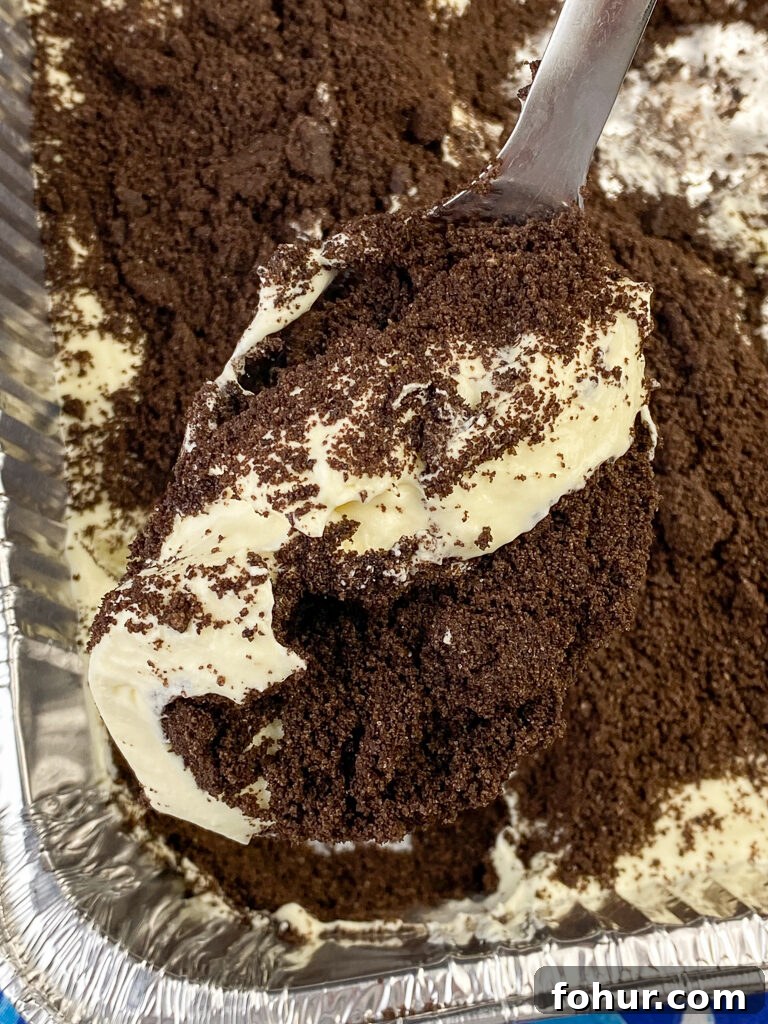 Dirt Cake Recipe to Feed a Crowd 4 Big serving spoon of dirt pudding with Oreo cookie pieces over top of a pan full