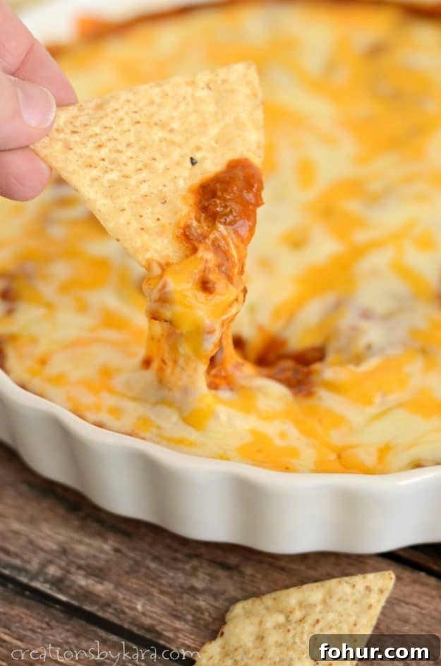 Chili Cheese Dip is the perfect appetizer for Game Day, New Years, or any party! scoop of chili cheese dip on a tortilla chip