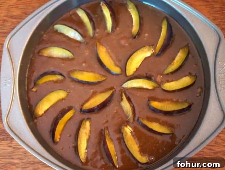 A pan full of cake batter and plums.